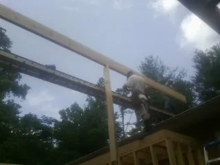 Carpenter setting a ridge beam over a new addition frame — Ice Dam Removal by Roofing Brothers in Newcomb