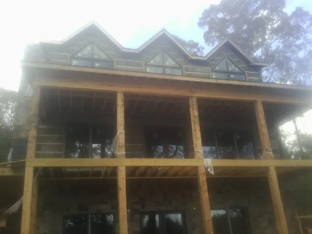 Dormers and porch framing on a large log home under construction — Roof Coating work by our crew in Newcomb