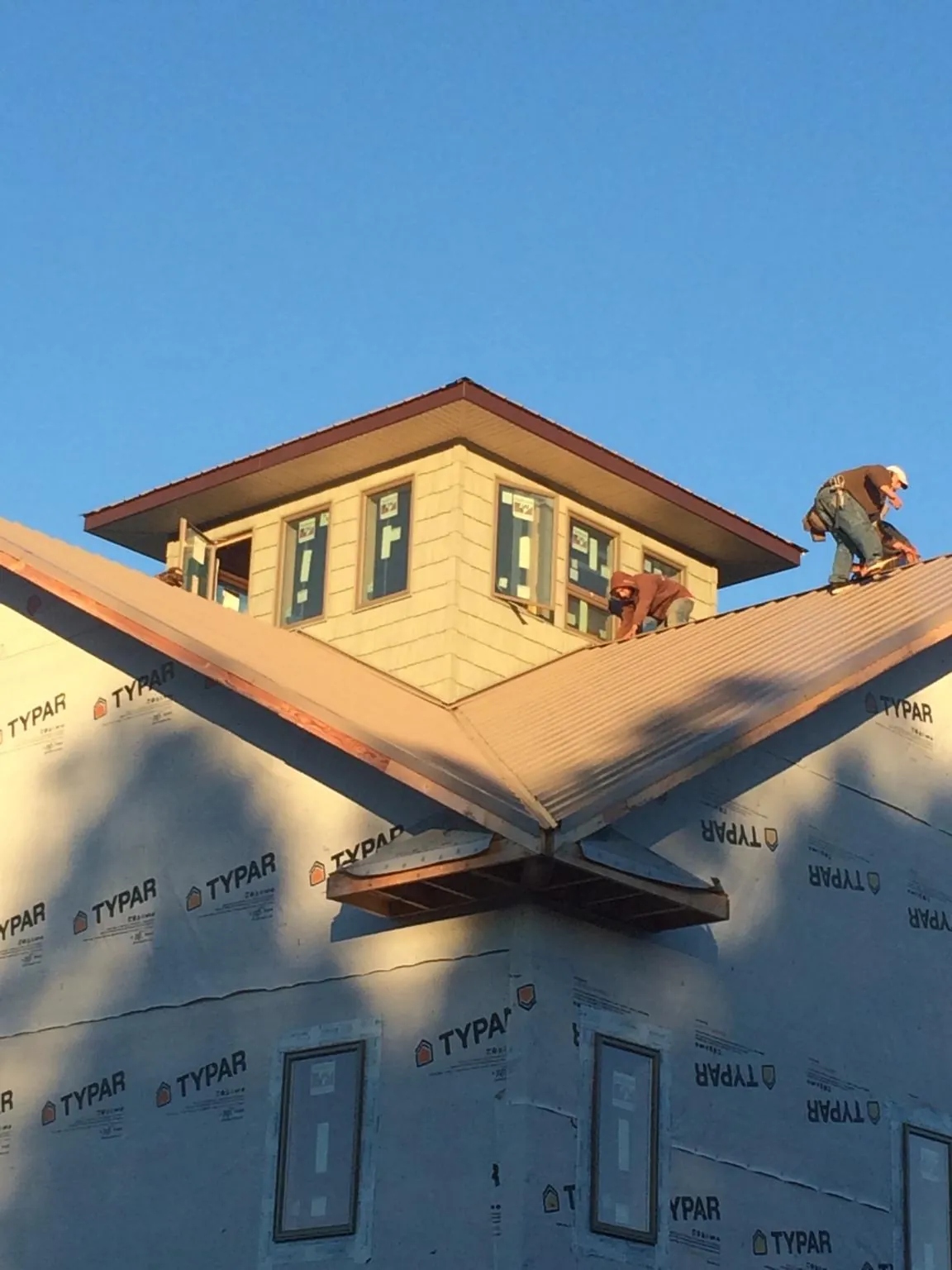 Roofers working around a rooftop cupola on a new metal roof at sunset — Roof Waterproofing in Newcomb by Roofing Brothers